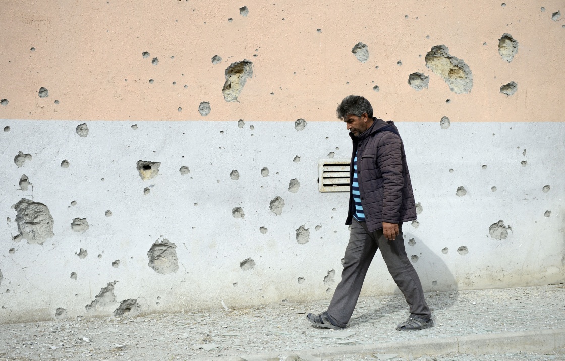 9月29日，在阿塞拜疆临近纳卡边境的塔塔尔地区，一名村民从布满弹孔的墙壁旁经过。新华社 图